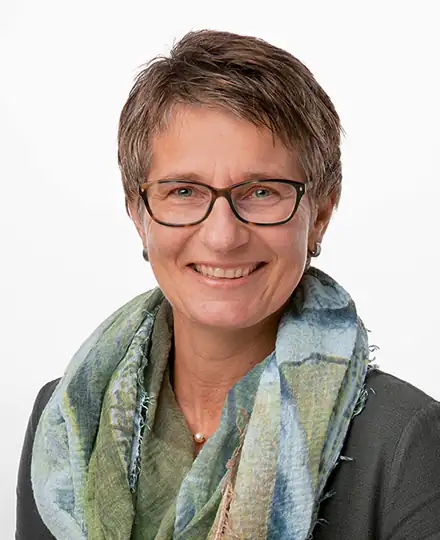 Eine freundlich lächelnde Frau mit Brille und Halstuch